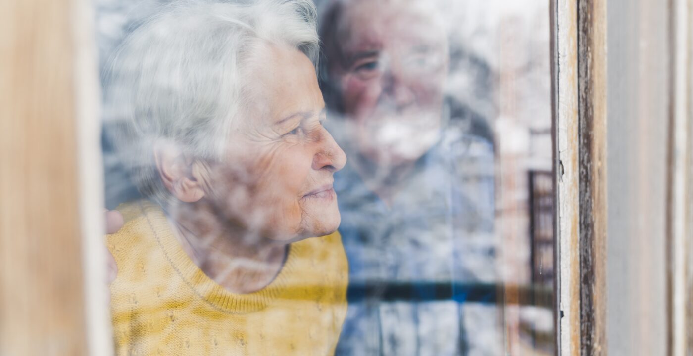 Altes Paar schaut aus dem Fenster