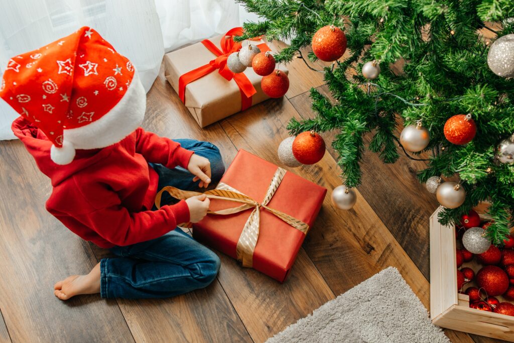 Kind unter dem Weihnachtsbaum mit Geschenken